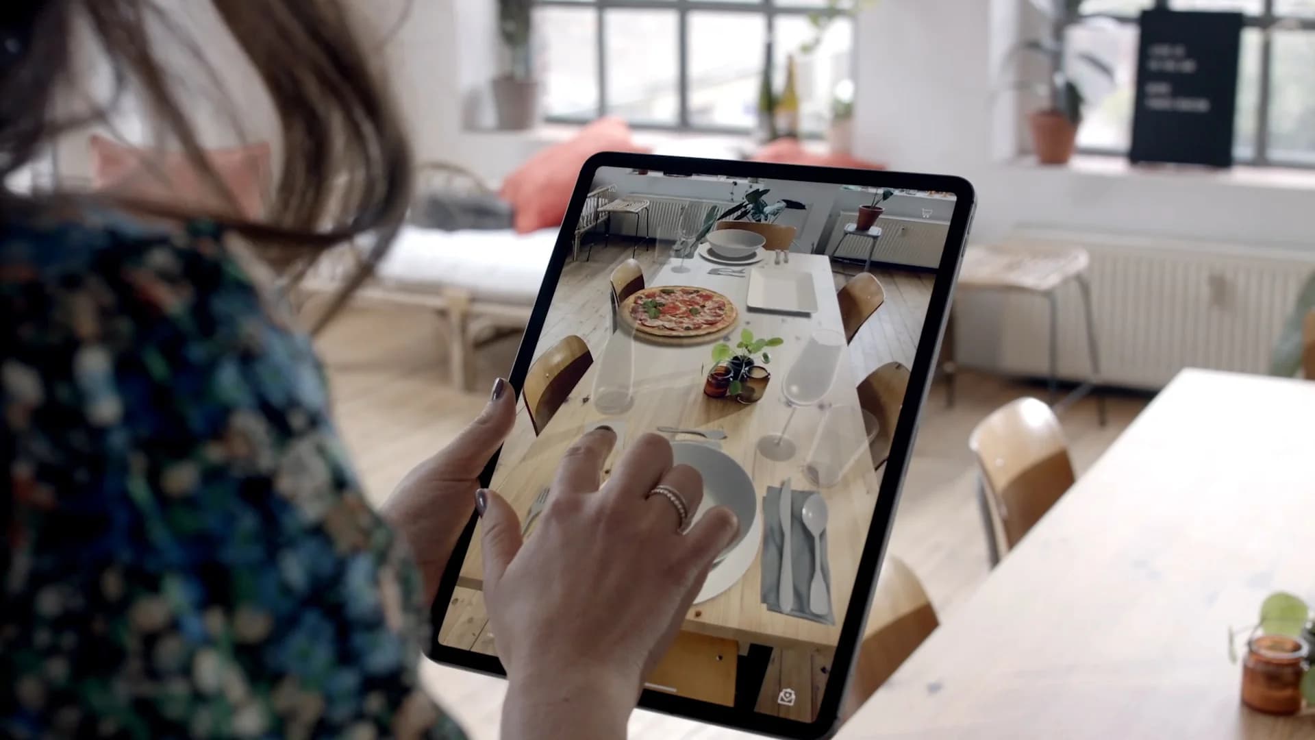 Mockup einer Person, die mit dem Smartphone AR-Objekte auf einem Esstisch platziert; warme, einladende Stimmung, Fokus auf Interaktion.