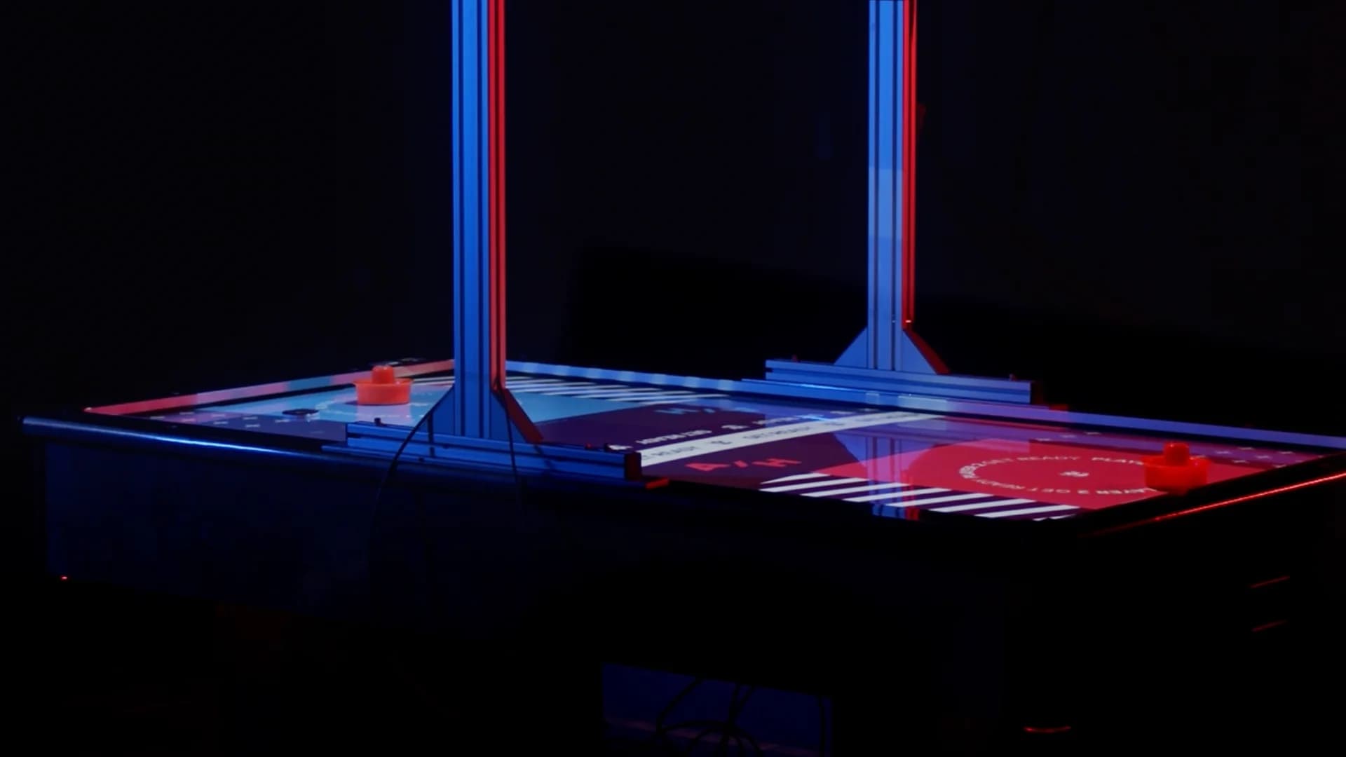 AR-Projektion auf dem Airhockey-Tisch mit bunten Overlays, Score-Anzeige und Puk-Trail; Spieler im Bild
