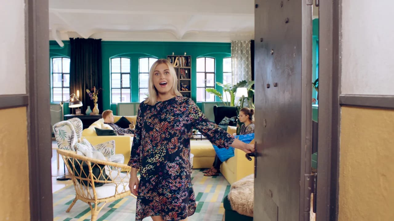 Smilla öffnet die Wohnungstür; Wohnzimmer mit Gästen, TV im Hintergrund und Smartphone in der Hand, atmosphärische Szene.