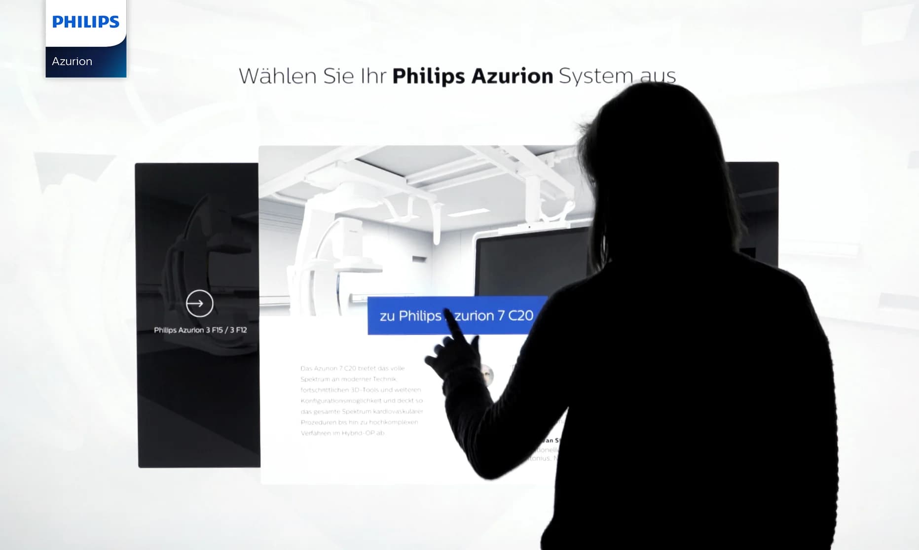 85‑Zoll Touch‑Terminal auf einem Messestand, Besucher interagiert mit dem 3D‑Modell des Philips Azurion.